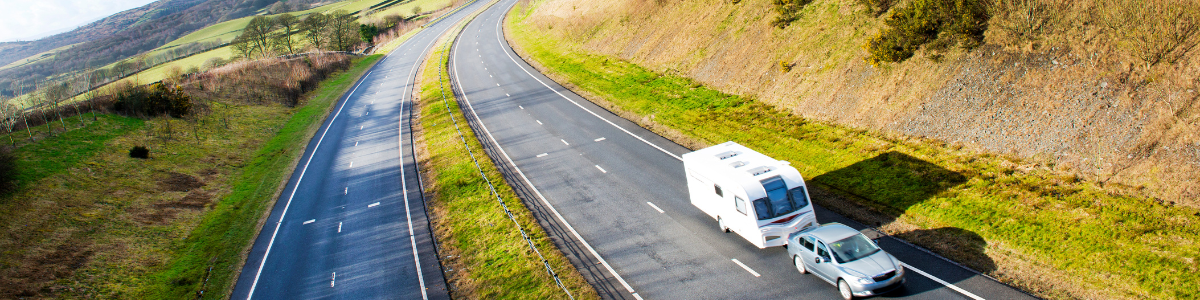Caravan cruising down a winding road, showcasing the freedom of travel with a caravan tv antenna booster for clear reception.