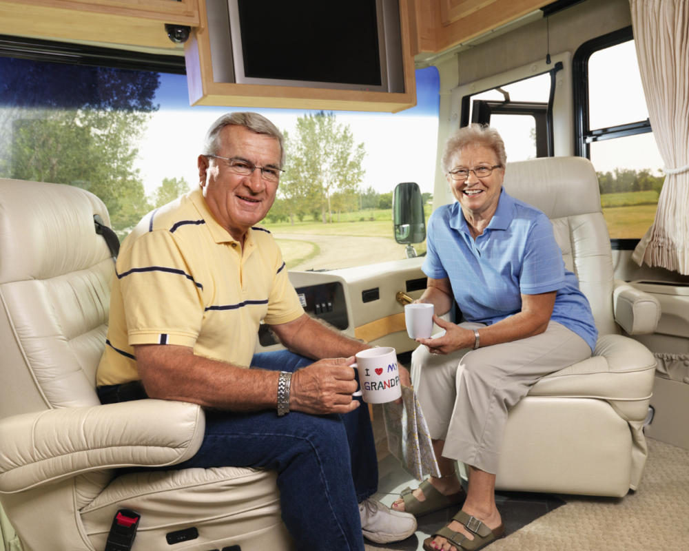 An older couple comfortably seated in their RV, enjoying a clear viewing experience thanks to their reliable rv tv antenna, with a TV visible in the background.